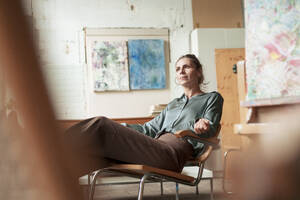 Painter sitting on chair in art studio - JOSEF22772