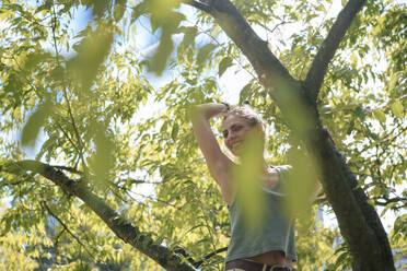 Glückliche Frau mit erhobenem Arm an einem Baum stehend - JOSEF22805