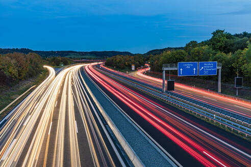 Deutschland, Baden-Württemberg, Leonberg, Fahrzeuglichtspuren entlang der Bundesautobahn 8 in der Abenddämmerung - WDF07500