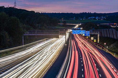 Deutschland, Baden-Württemberg, Leonberg, Fahrzeuglichtspuren entlang der Bundesautobahn 8 in der Abenddämmerung - WDF07502