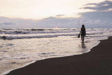 Frau, die an der Küste am Strand spazieren geht - PCLF00959