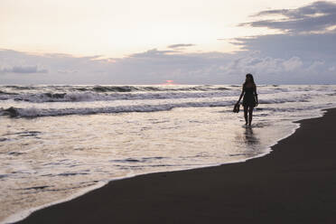 Woman walking on coastline at beach - PCLF00959