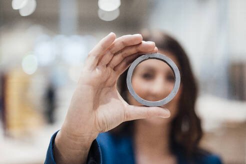 Businesswoman with metal circle in industry - JOSEF22897