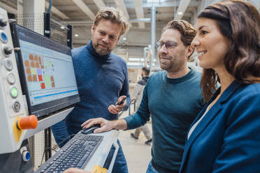 Lächelnde Geschäftskollegen bei der Arbeit am Computer in einer Werkstatt - JOSEF22907