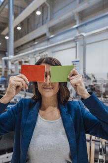 Businesswoman covering eyes with wooden pieces in industry - JOSEF22916