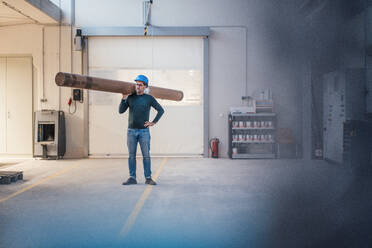 Zimmermann trägt Holzpfeiler auf der Schulter in der Industrie - JOSEF22925
