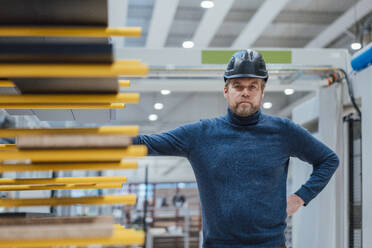 Selbstbewusster Architekt mit Schutzhelm an Holzplanken in der Industrie - JOSEF22965