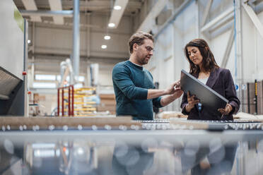 Business colleagues discussing over solar panel in workshop - JOSEF22997