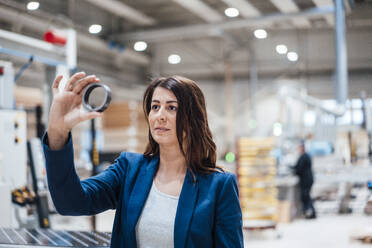 Businesswoman examining metal circle in industry - JOSEF23003