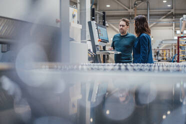 Businessman discussing strategy over computer with colleague in industry - JOSEF23006