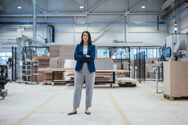 Businesswoman with arms crossed standing in industry - JOSEF23041