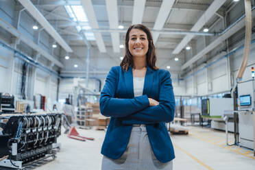 Happy businesswoman in blazer with arms crossed at workshop - JOSEF23042