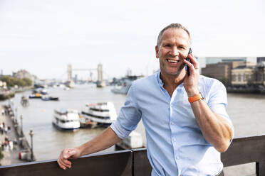 Happy businessman talking on smart phone in London, UK - WPEF08013