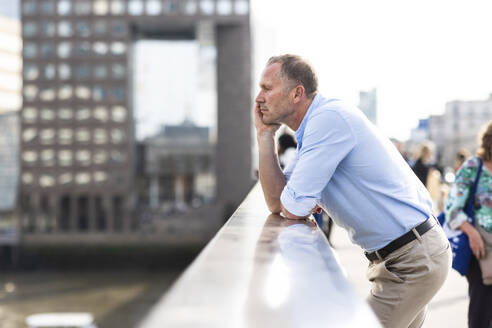 Nachdenklicher Geschäftsmann lehnt auf einer Brücke in London, UK - WPEF08025