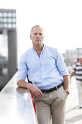 Mature businessman with hand in pocket standing on bridge - WPEF08027