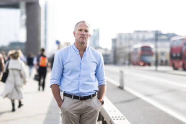 Businessman standing with hands in pockets on footpath - WPEF08028