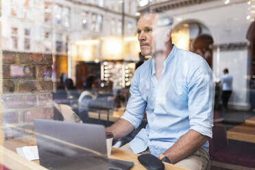 Businessman sitting with laptop in cafe - WPEF08030