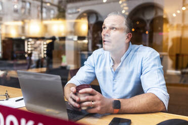 Businessman holding coffee cup at cafe - WPEF08037