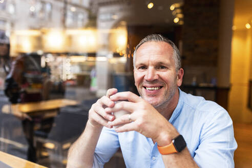 Happy businessman having coffee at cafe - WPEF08038