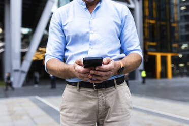 Businessman using smart phone at office park - WPEF08046