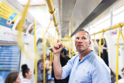 Geschäftsmann hält Handgriff und pendelt durch Zug - WPEF08065