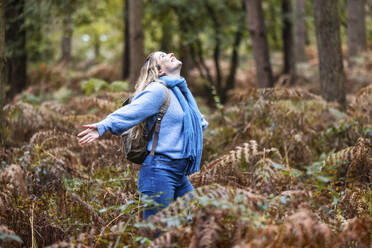 Sorglose Frau mit ausgestreckten Armen im Wald von Cannock Chase - WPEF08085