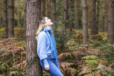 Glückliche Frau lehnt an einem Baum im Cannock Chase Forest - WPEF08093