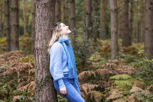 Glückliche Frau lehnt an einem Baum im Cannock Chase Forest - WPEF08093