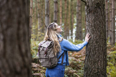 Glückliche Frau berührt Baumstamm im Cannock Chase Forest - WPEF08095