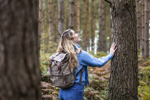 Happy woman touching tree trunk in Cannock chase forest - WPEF08095