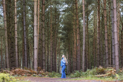 Frau steht mit Rucksack in der Nähe von Bäumen im Cannock Chase Forest - WPEF08097