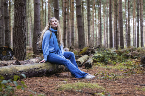 Nachdenkliche Frau sitzt auf einem Baumstamm im Cannock Chase Forest - WPEF08099