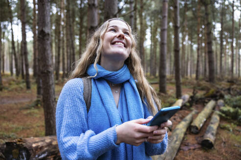 Glückliche Frau mit Smartphone in Cannock Chase Forest - WPEF08104