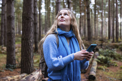Nachdenkliche Frau mit Smartphone im Cannock Chase Forest - WPEF08105