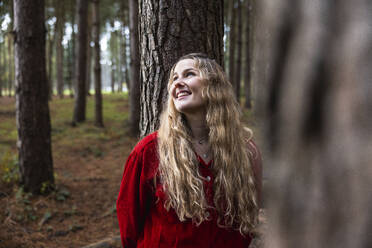 Glückliche schöne Frau lehnt sich an einen Baumstamm im Cannock Chase Forest - WPEF08110