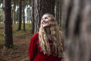 Glückliche schöne Frau lehnt sich an einen Baumstamm im Cannock Chase Forest - WPEF08110