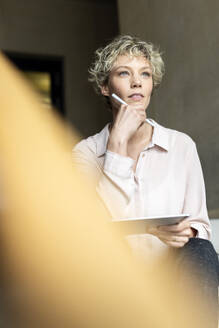 Thoughtful businesswoman with tablet PC at workplace - PESF04174