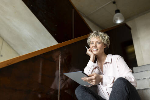 Businesswoman with tablet computer sitting on steps - PESF04177