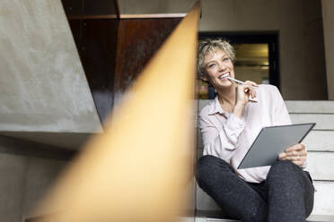 Glückliche Geschäftsfrau mit Tablet-PC auf einer Treppe sitzend - PESF04178