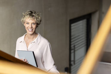 Lächelnde Geschäftsfrau mit Tablet-Computer an der Wand - PESF04183