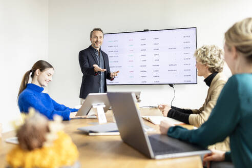 Mature businessman giving presentation to colleagues in board room - PESF04206