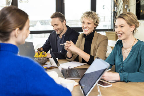 Happy colleagues discussing business strategy in meeting at workplace - PESF04217