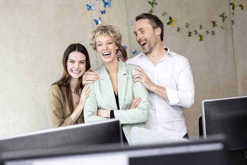 Businesswoman laughing with colleagues at workplace - PESF04239