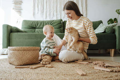 Mutter hält Katze und spielt mit Sohn im Wohnzimmer - WESTF25296