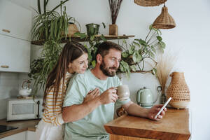 Affectionate couple sharing mobile phone at home - WESTF25329