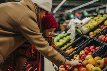 Junge Frau und Sohn kaufen Äpfel im Supermarkt - VSNF01544