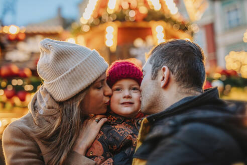 Father and mother kissing son at Christmas market - VSNF01547