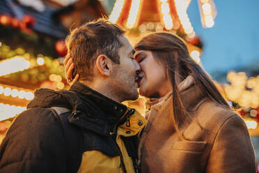 Verliebtes Paar küsst sich auf dem Weihnachtsmarkt - VSNF01549