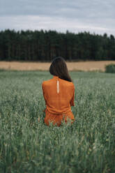 Frau steht inmitten grüner Maiskörner auf einem Feld - TOF00172