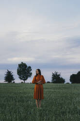 Frau stehend im Maisfeld vor dem Himmel bei Sonnenuntergang - TOF00184